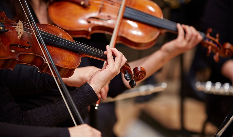 Nahaufnahme von zwei Personen, die Geige spielen, Fokus auf den Händen und den Instrumenten.